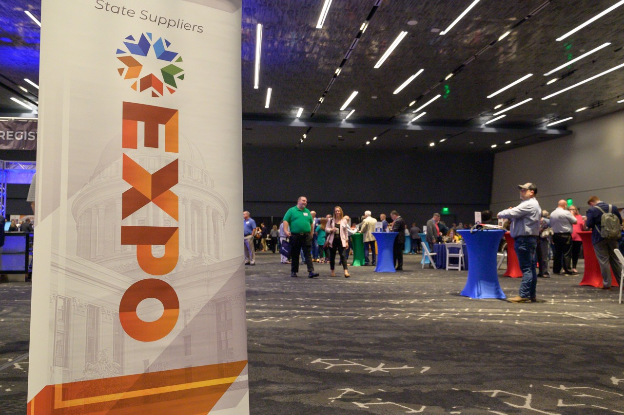 2023 Expo standing banner with ballroom and attendees in the background.