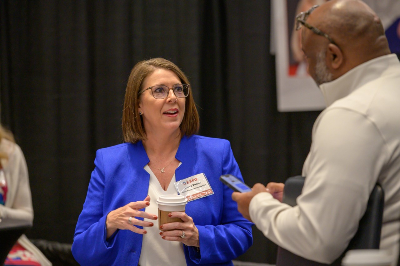 Jenny Virden holds coffee and talks to attendee at the Public Safety cabinet booth.