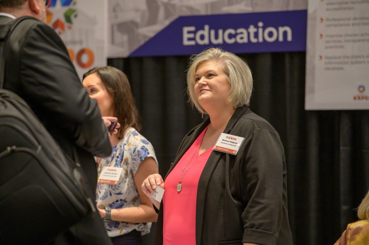 Melissa Ahlgrim talks to an attendee at the Education cabinet booth.
