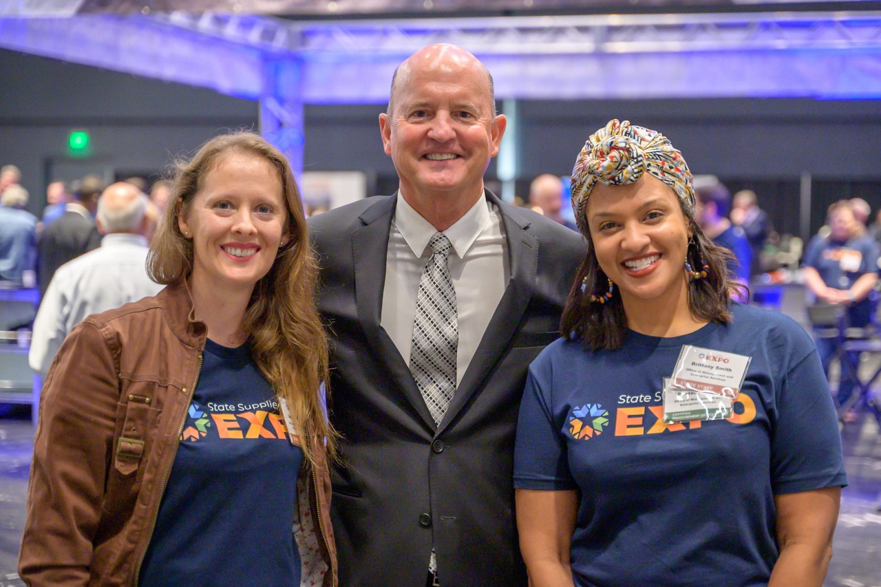 State Chief Operating Officer John Suter smiling with Brittany Smith and Sarah Mouton.