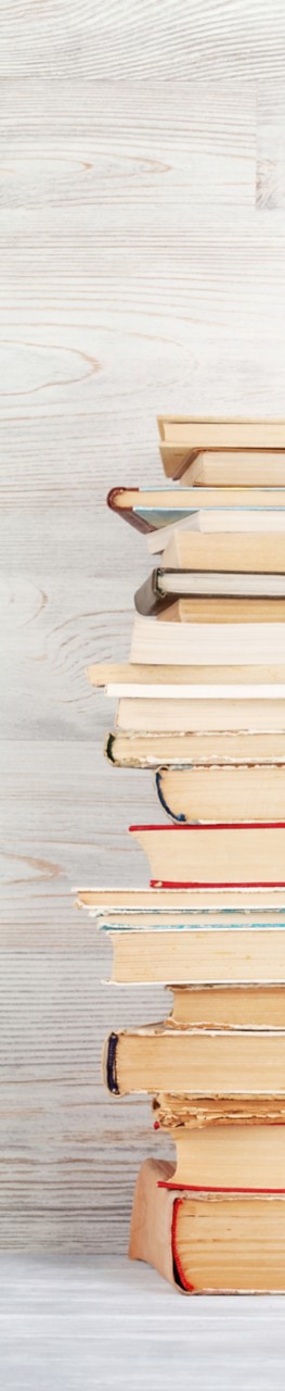 Stack of old books in front of wooden wall. School background. Education backdrop