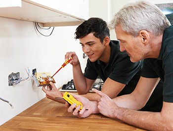 Electrician With Apprentice Working In New Home