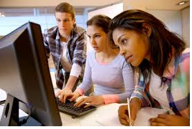 Academic picture of three students looking at a computer monitor