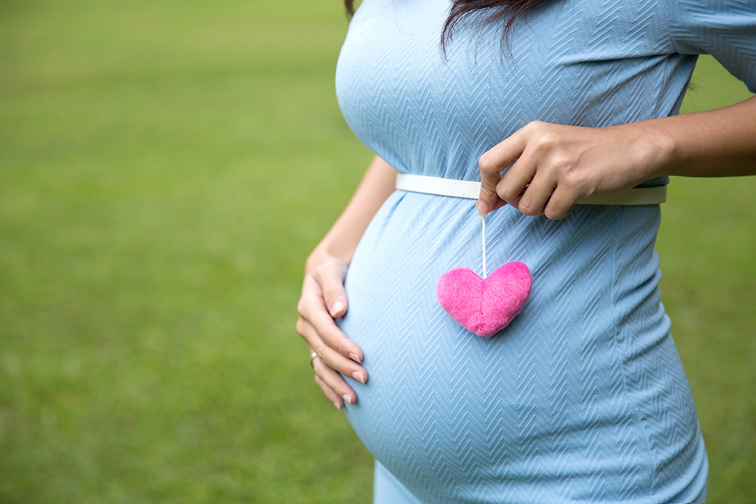 pregnant woman in blue dress holding a single heart shape access
