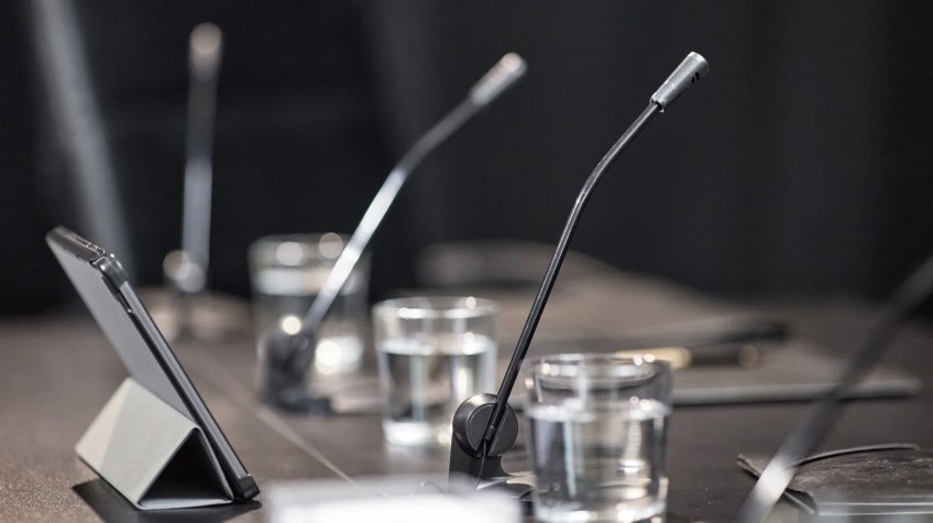 Board meeting table with glasses of water, microphones and tablet