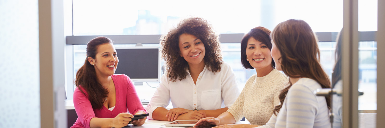 Women colleagues in a office gathered around a table for a meeting
