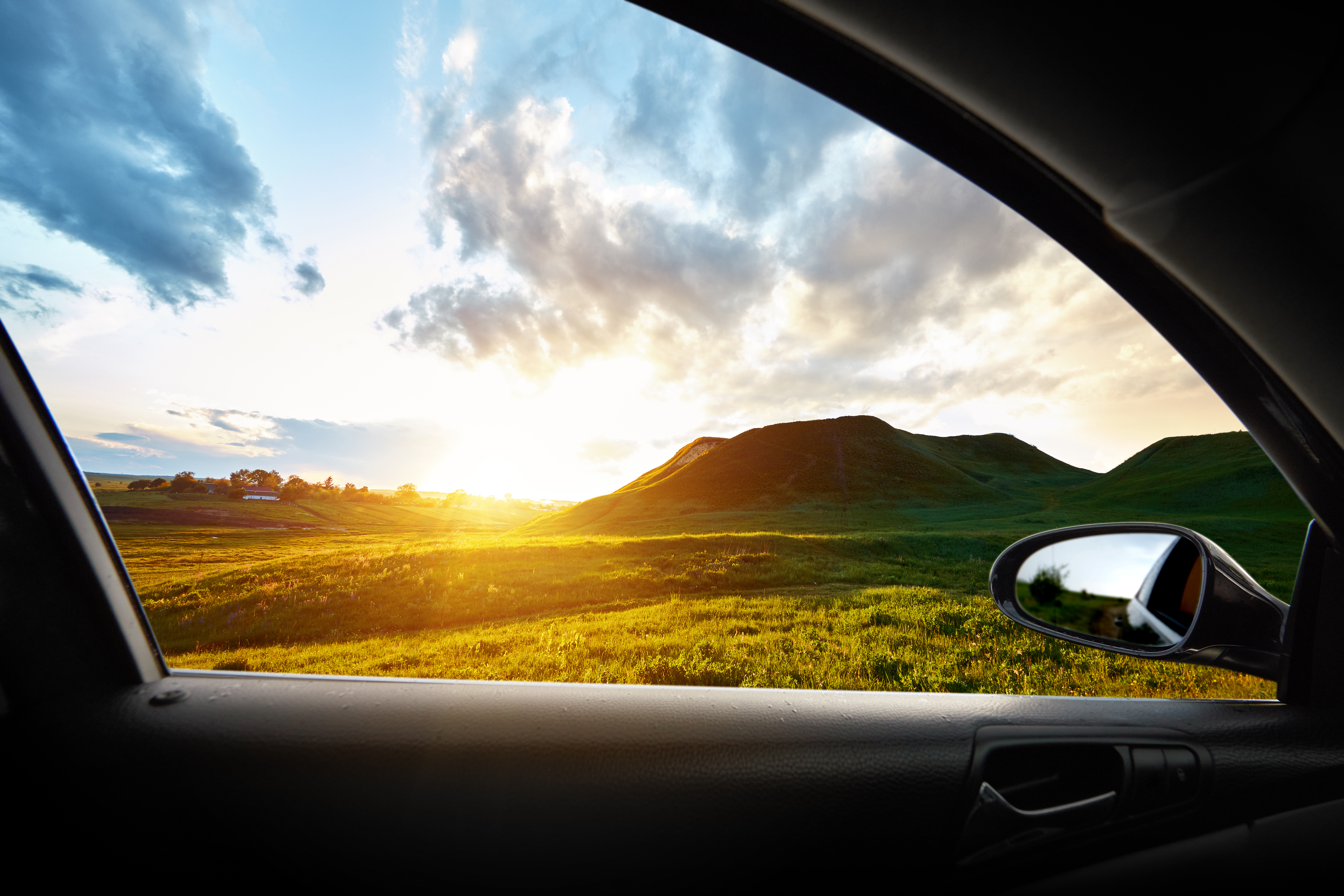 green hill at sunset from inside a car