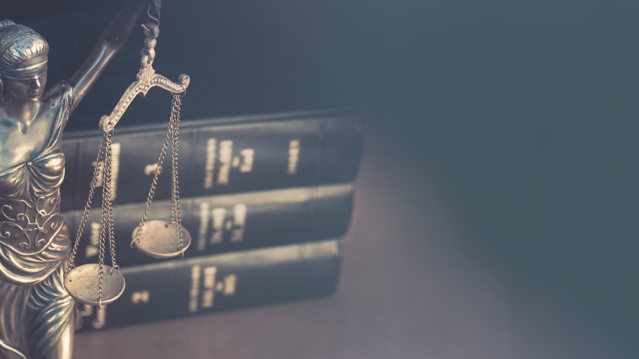 Lady Justice statue with a books behind her.