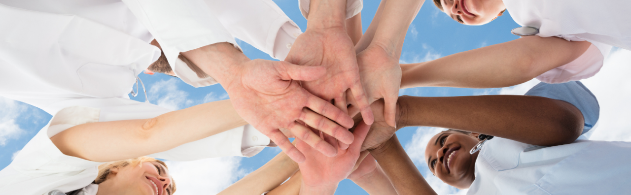 A group of nurses standing in a circle with all of their hands laid on top of each other.