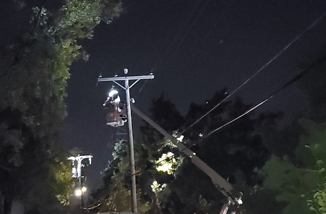 Linemen working on power poles and lines at night during an ice storm