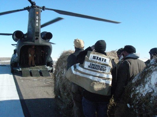 State Emergency Management helping roll hay bales onto Chinook.