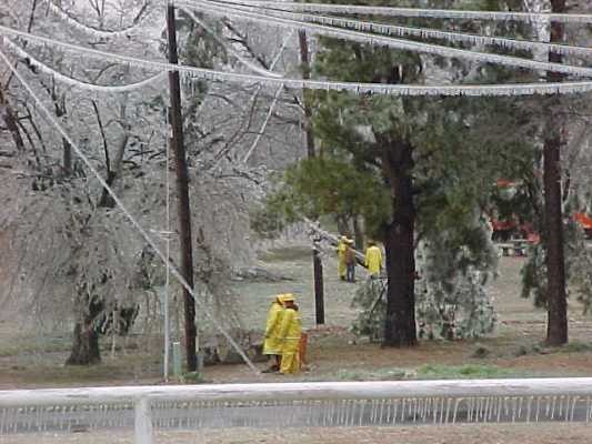 Iced over power lines with people assess the area. 