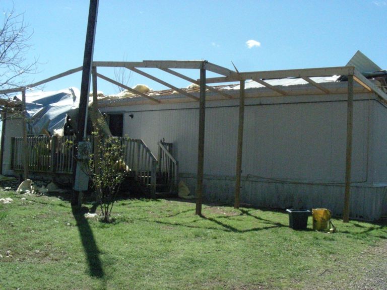 house with damage from storm and roof almost completely gone. 
