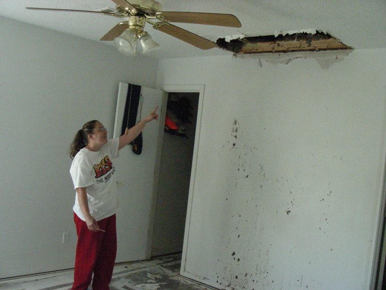 Sheet rock damage in a house with the home owner pointing to the hole in the ceiling. 
