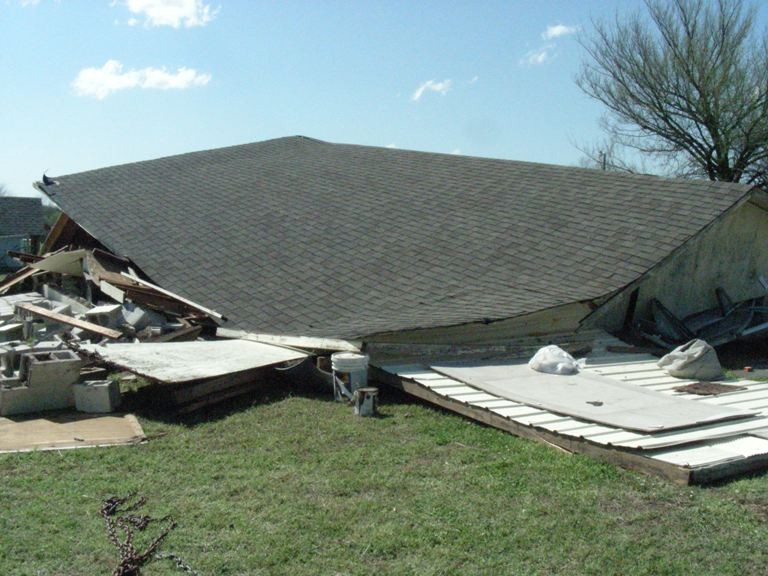 a house with total damage and the roof collapse on the foundation. 