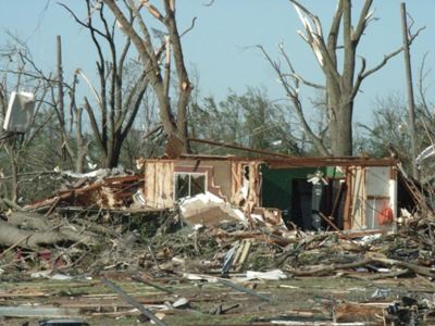 tornado damaged home missing front wall.