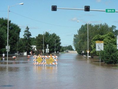 A flooded road with detour signs in water. 