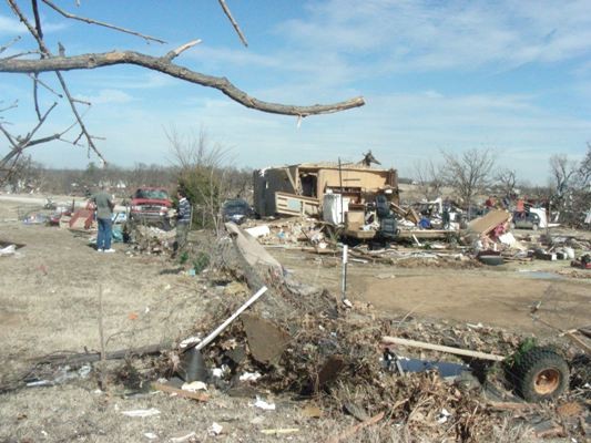 storm damage to a builiding and debris scattered all over. 