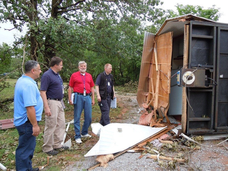 Four men looking a storm damage of a building. 