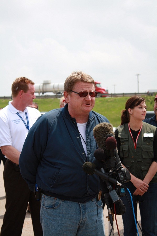 A man in front of the media's microphone outside.
