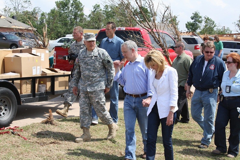 Gov. Henry and his wife with a lot of people behind them walk the storm ravaged area. 