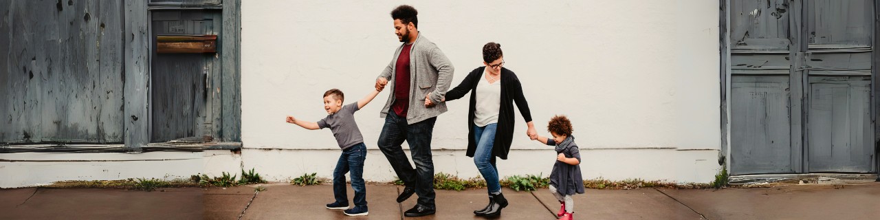 A young family walking down sidewalk.