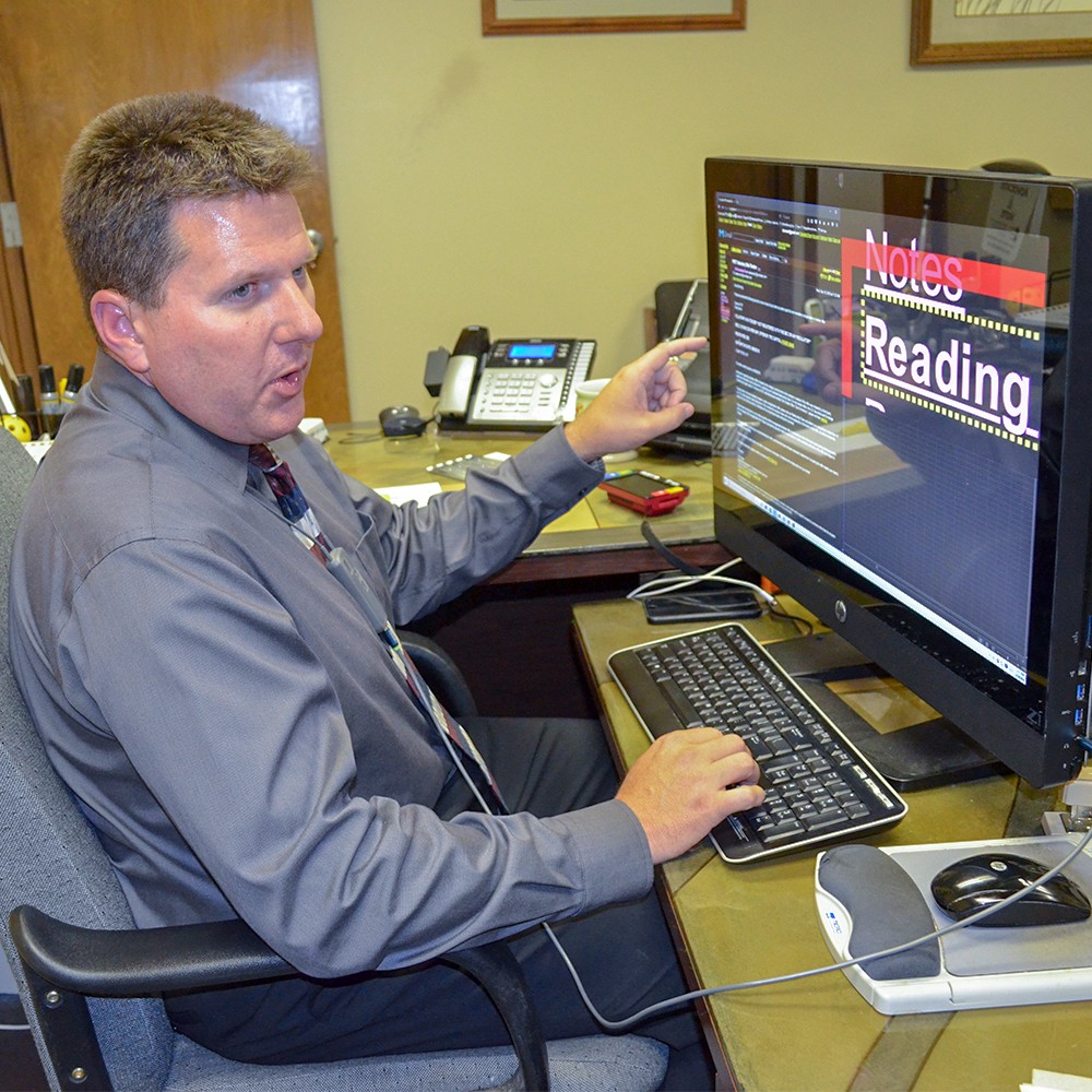 A man using a large computer monitor with a text enlarging software.