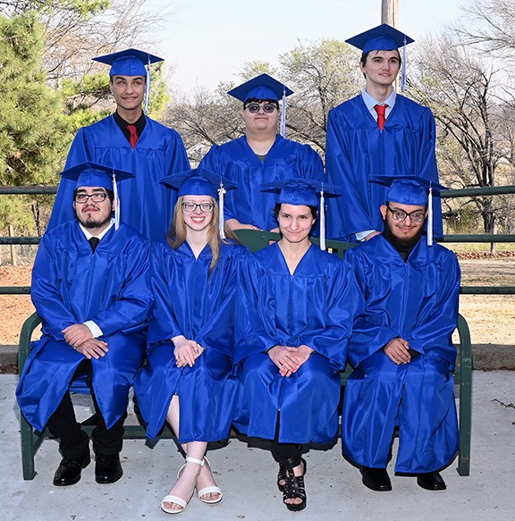 Seven seniors wearing graduation caps and gowns.