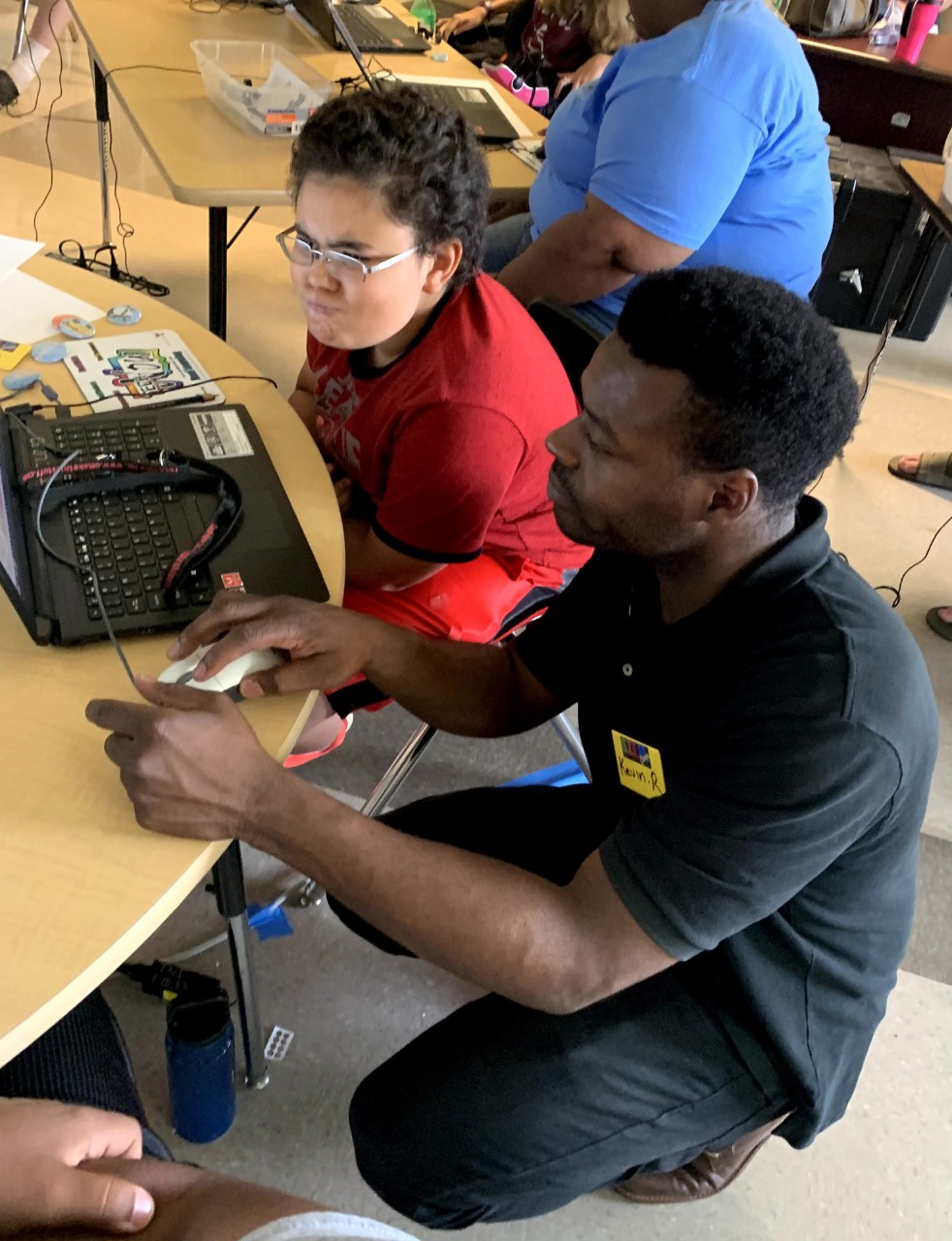 A teacher helps a student on the computer