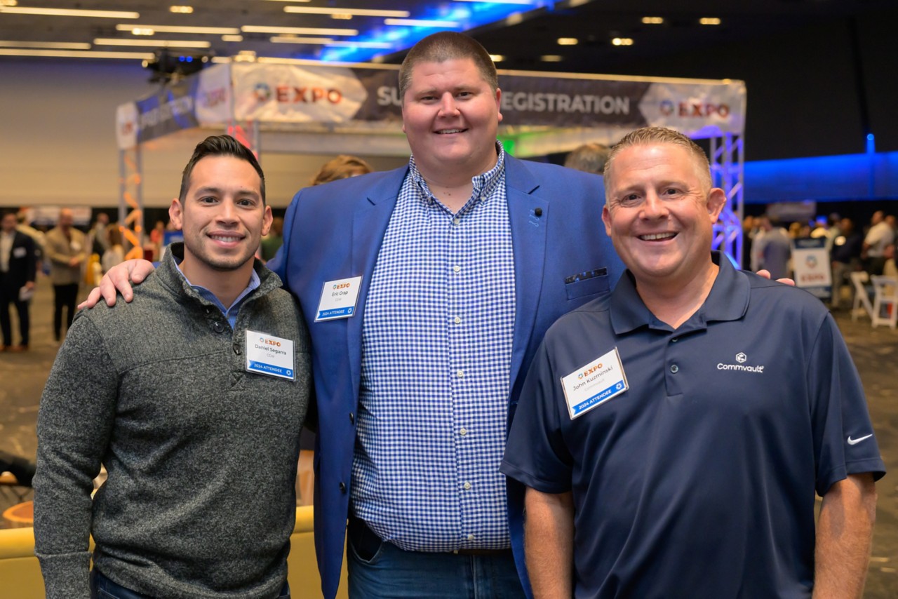 Three attendees stand smiling together