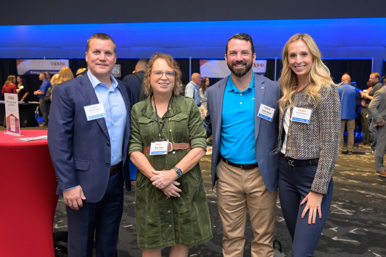 Four attendees stand in a group smiling for a photo