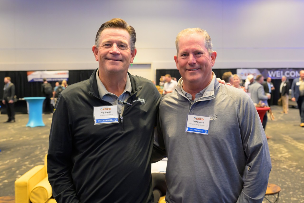 Two attendees stand together smiling