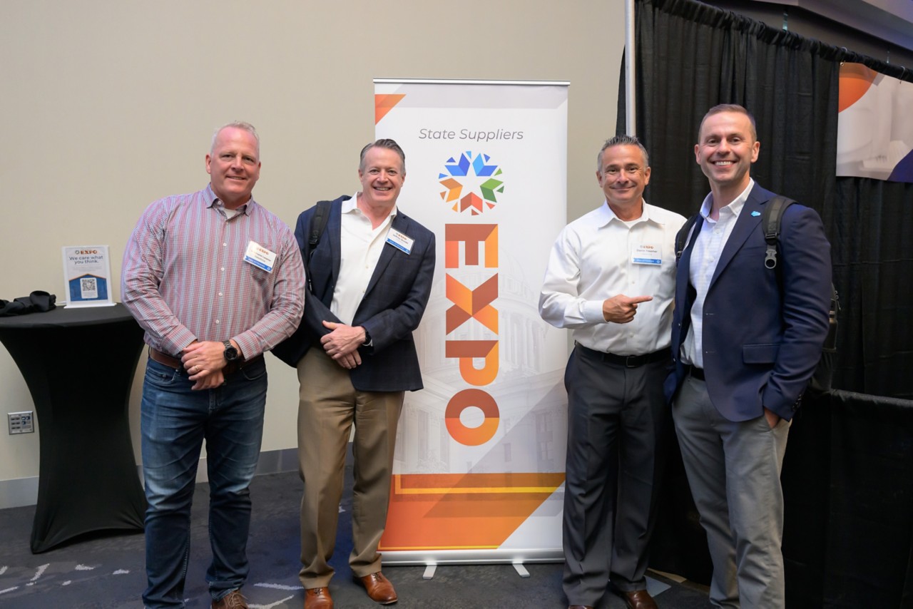 Four Salesforce attendees group photo in front of event banner