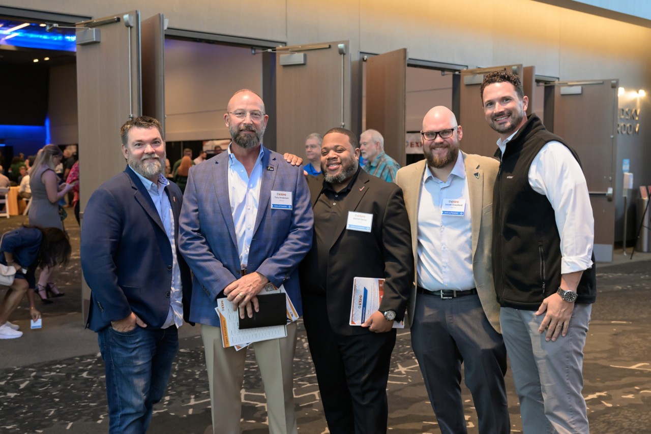 Five Verizon attendees pose for group photo in front of ballroom doors