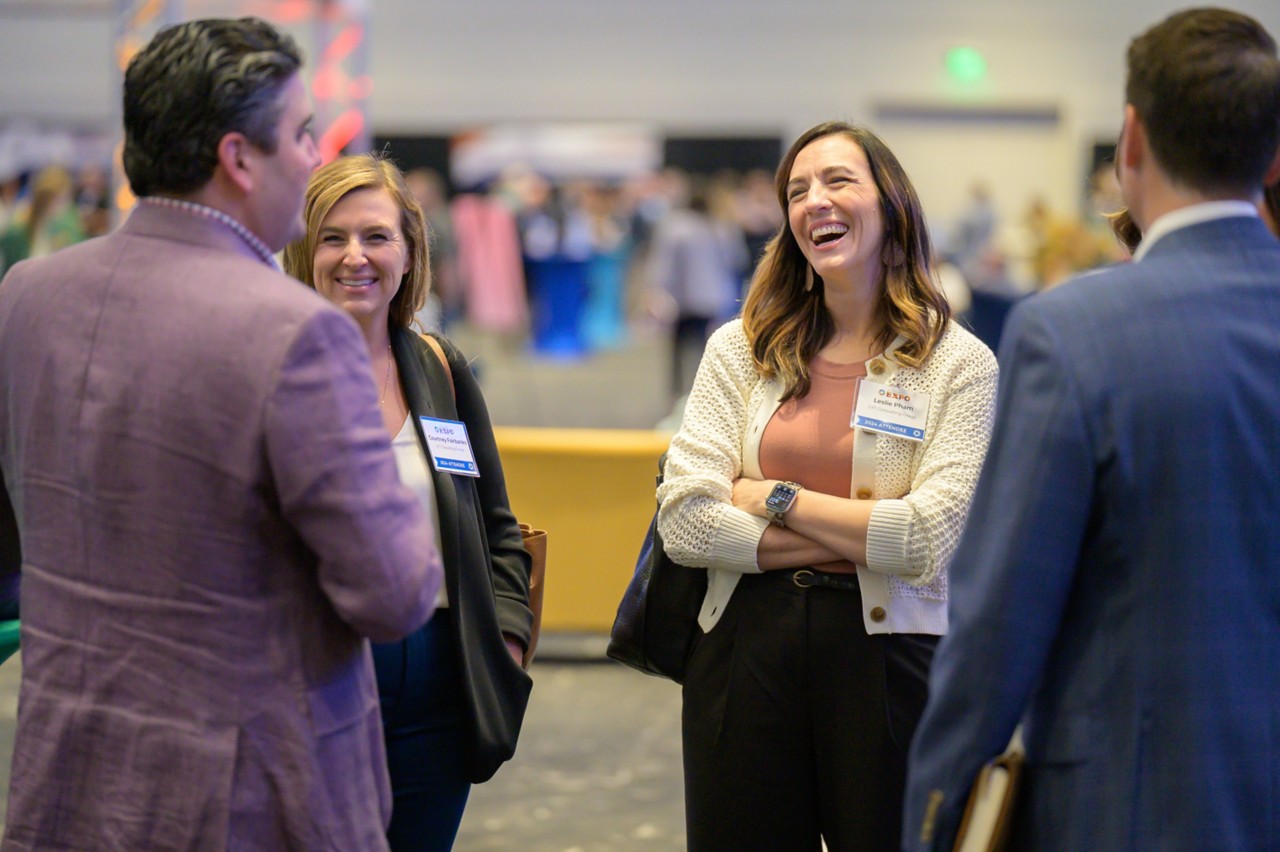 Four attendees standing together laughing