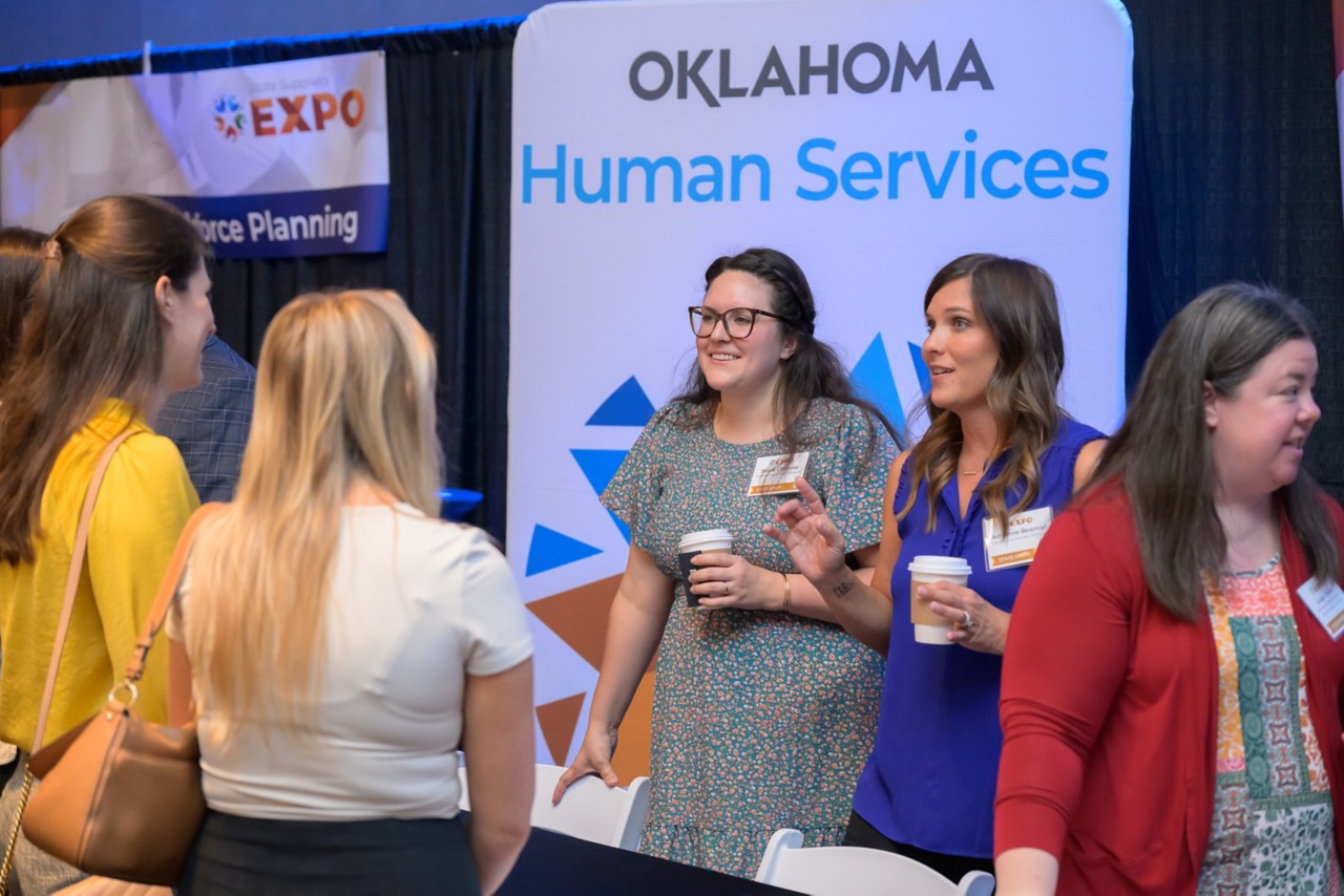 Group smiling and having coffee at the Human Services booth