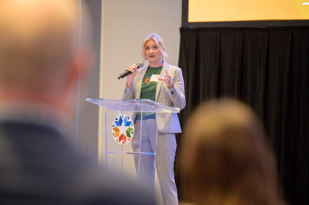 State Purchasing Director Amanda Otis speaking during general session as seen from the audience