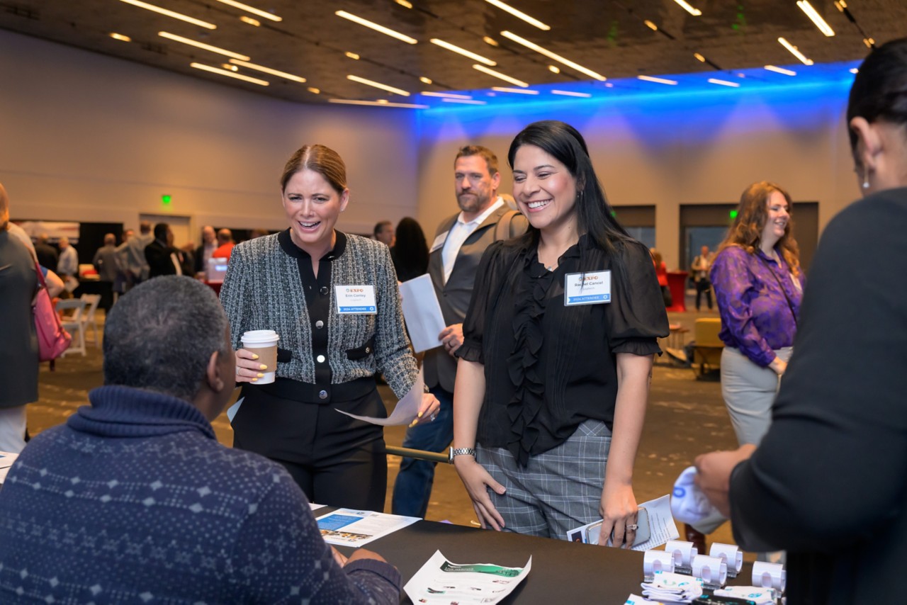 Two attendees engage with a staff member at a booth