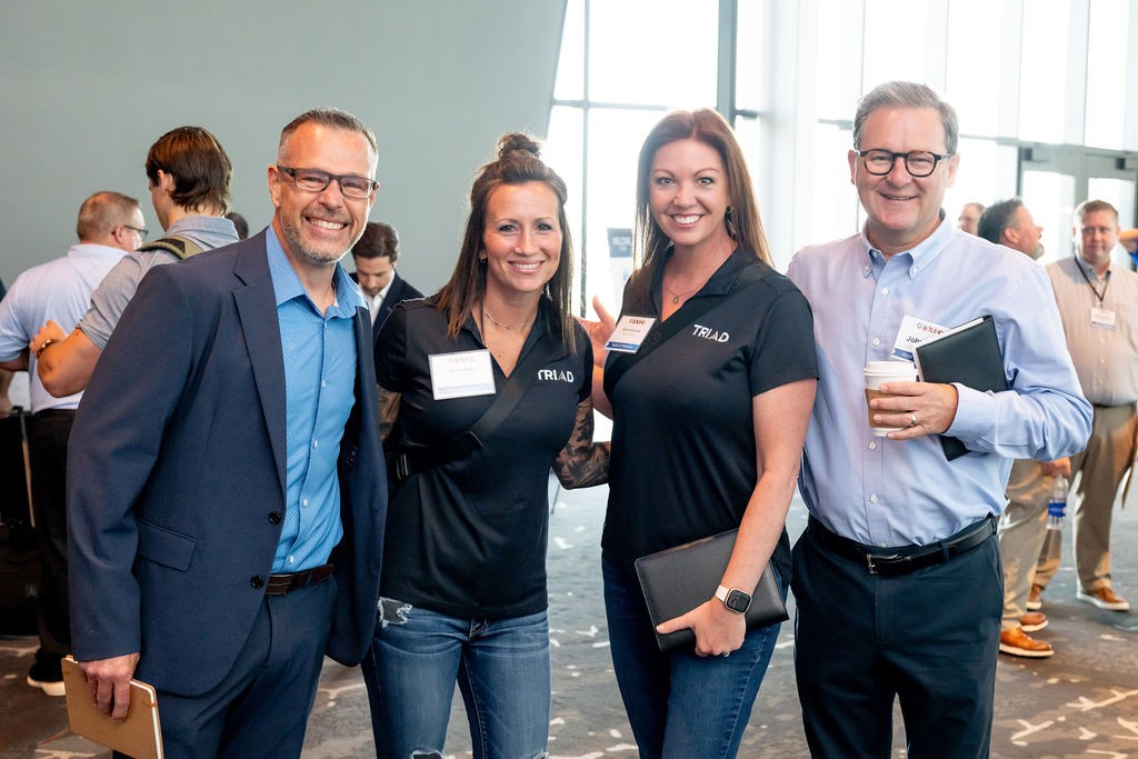 Four supplier attendees smiling in the event check-in area