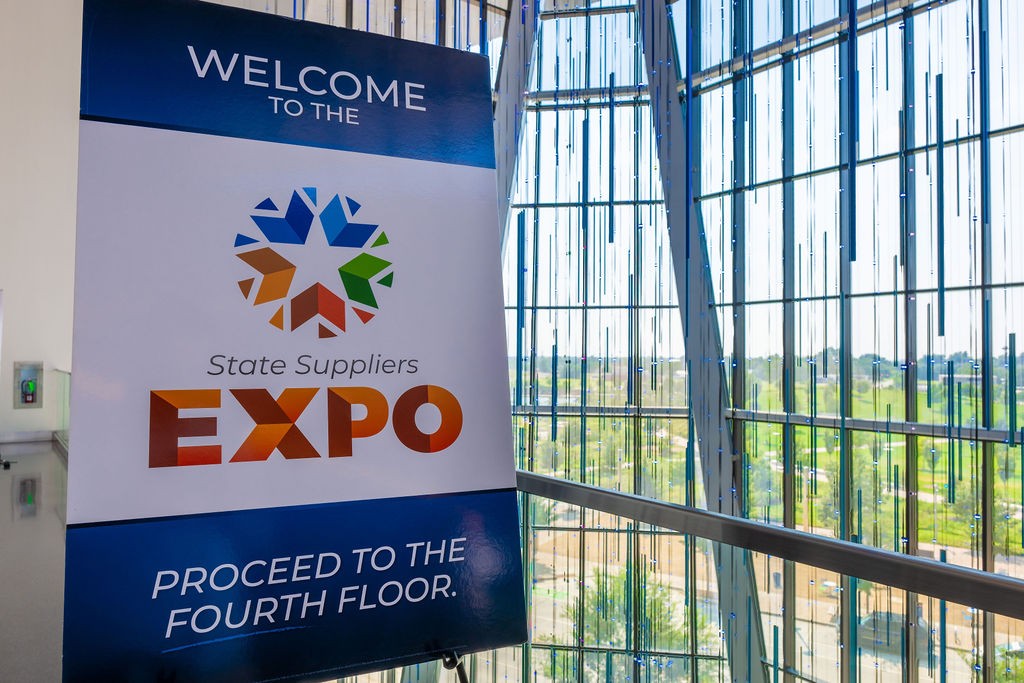 Event welcome sign inside venue with Scissortail Park visible through the windows