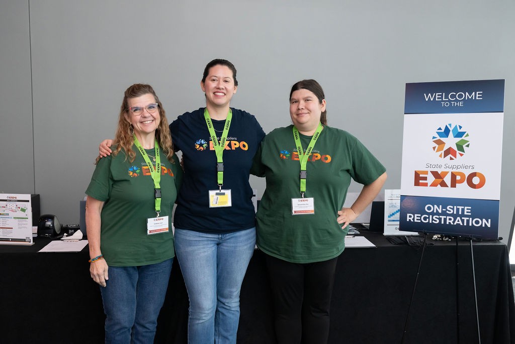 On-site registration staff smiling next to welcome sign