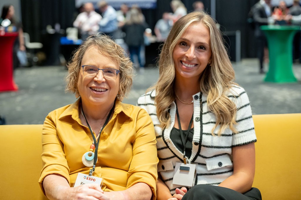 Two attendees smiling on yellow couch