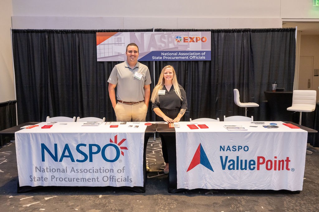 Two NASPO employees smile at the National Association of State Procurement Officials booth