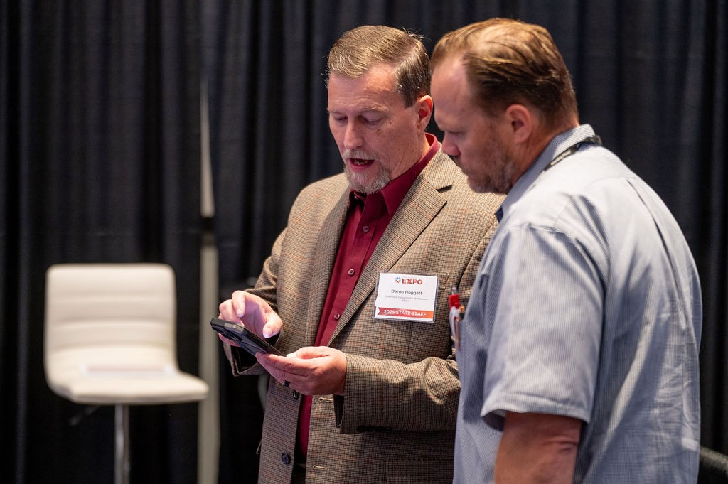 ODVA employee Daron Hoggat shows attendee something on cellphone