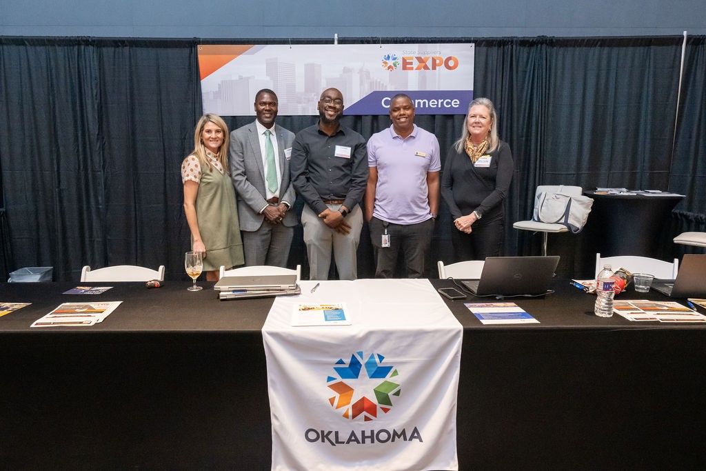 Oklahoma Department of Commerce staff smiling at the Commerce booth