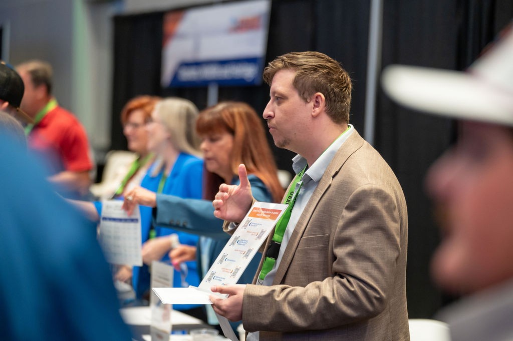 OMES Central Purchasing employee Barry Timberlake shows flyer to attendee at Statewide Contracts booth