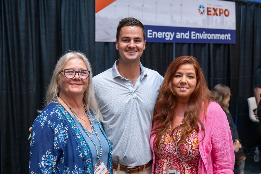 Three CLO employees smiling at the Energy and Environment booth