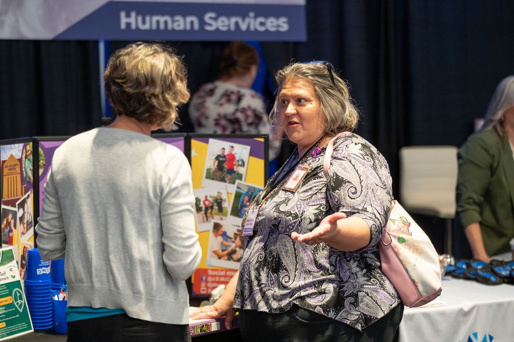 Two suppliers talk at Human Services booth