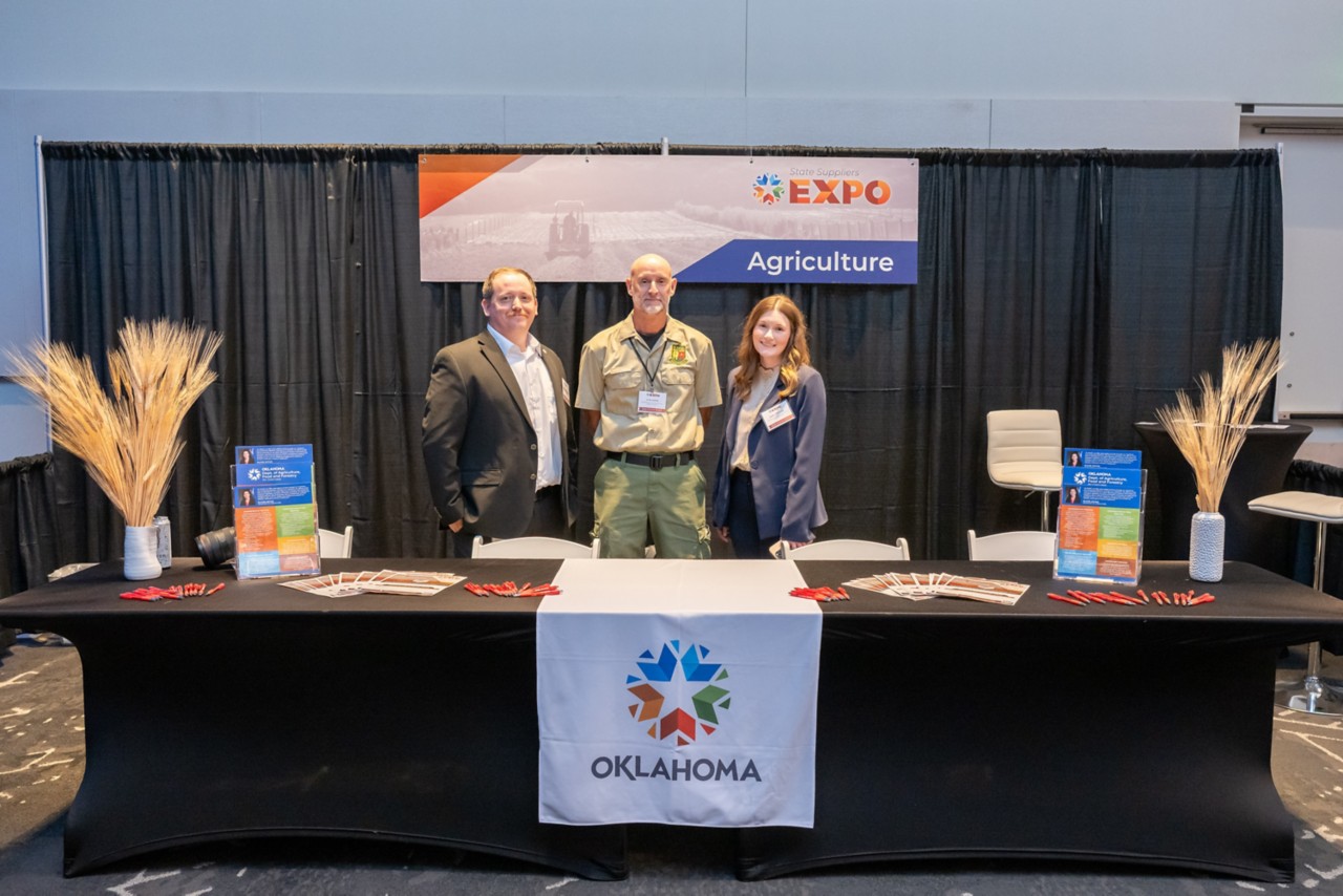 three people standing and smiling in agriculture expo booth
