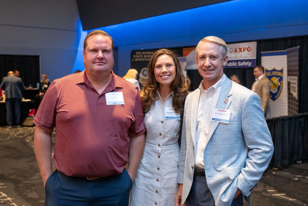 Three suppliers smiling in front of Public Safety booth
